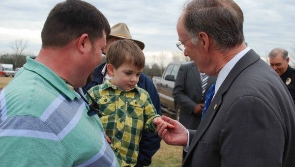 Gov. Robert Bentley shakes hands with 2-year-old Tucker Coggins, held by Andrew Coggins. Tucker and Andrew are the nephews of Debi and Clark Coggins who had to receive medical treatment after their home on County Road 2214 was destroyed by a tornado on Christmas night. 