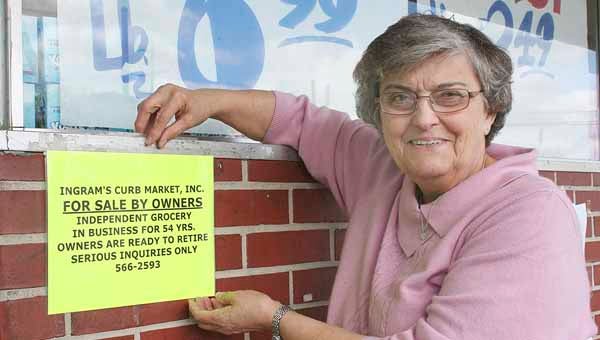 Charlene Ingram shows off a sign now posted at Ingram’s Curb Market in Troy. Ingram said she plans to sell the family-owned business.