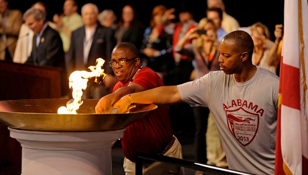 Raymond Ervin, left, of Anniston, and Lt. Leo Smith, of the Birmingham Police Department, light the torch during the 2013 Alabama State Special Olympics Opening Ceremonies in Troy, Ala., Friday, May 17, 2013. (Photo/Thomas Graning)
