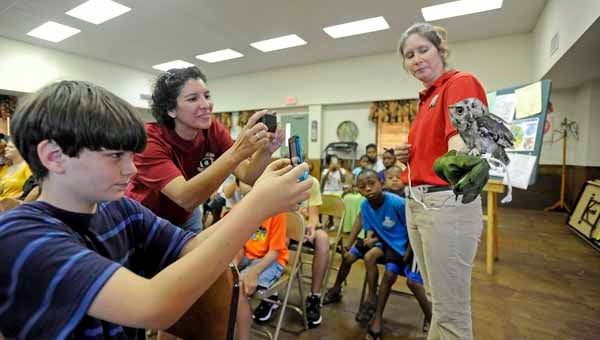 Representatives from the Montgomery Zoo presented various birds of prey as part of the summer reading program at the Tupper Lightfoot Memorial Library in Brundidge Thursday. Jesse Nicholson and Alette Hatfield take photographs as Jennifer Hutcheson presents a Screech Owl.