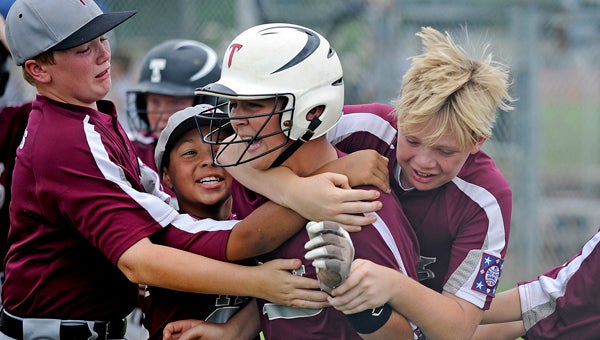 Troy players celebrate with Jade Sikes (32) after Sikes hit a two-run homerun in the sixth inning to tie the the state championship game against AUM in Muscle Shoals, Ala., Thursday, July 11, 2013. Troy won 9-8 in seven innings. (Photo/Thomas Graning)
