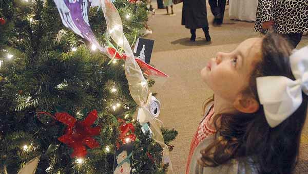 PHOTO by Jaine Treadwell   A little girl gazes up at the lights and decorations on a tree at the Johnson Center for the Arts Sunday.