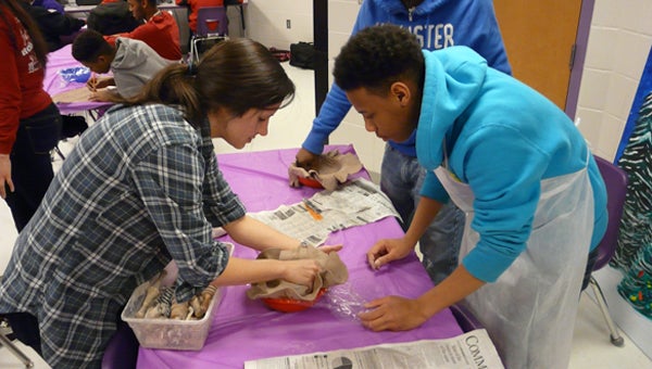 Troy art student Cayla Whitt assists a PCHS student in making a bowl for the Empty Bowls fund-raiser.