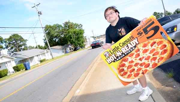 Messenger Photo/ mona moore John Canant holds a Little Caesar’s sign on South Brundidge Street. Canant says he loves interacting with passersby and jamming out to music while he works. 