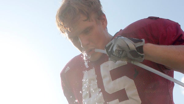Daniel Warren cools off during a hot, muggy Troy football practice Thursday afternoon by getting a sip of water from the team’s water cooler.  Messenger Photo/Ryan McCollough