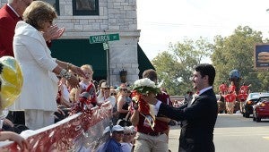 Delta Chi fraternity member hands flowers to Janice Hawkins, first lady for Troy University, during Saturday's homecoming parade.  MESSENGER PHOTO/SCOTTIE BROWN