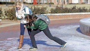 Ragan Eaves grabs for support from Moriah Brannon while walking across an ice-covered walkway near a fountain at Troy University. MESSENGER PHOTO/SCOTTIE BROWN
