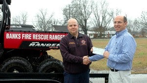 Banks Volunteer Fire Department Assistant Chief Jake DuBose accepts a $10,000 grant-check from Rick Cozine, manager of sales and marketing for Plum Creek Lumber and Timber.  MESSENGER PHOTO/SCOTTIE BROWN