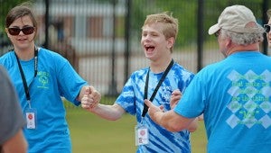 Pike County athlete Brandon Rhodes crosses the finish line with the help of Carla Faulkner during the 2015 Alabama Special Olympics summer games in Troy, Ala., Saturday, May 16, 2015. (Photo/Thomas Graning)