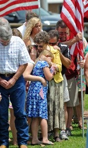 Helion Motes hugs a family member during after posting a flag for a loved one who sacrificed his life in service.