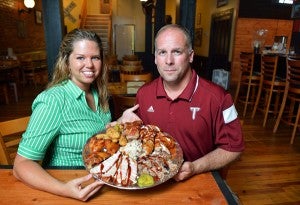 Messenger photo/Thomas Graning Sweet Rack Rib Shack is featured in “100 Best Barbecue Restaurants in America,” a book about a man’s 365-day journey to visit restaurants across the country. Amanda and Chris Dickens, owners of Sweet Rack, show off a tray of some of the food they offer in their restaurant. Sweet Rack Rib Shack is located on The Square in Downtown Troy.