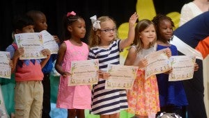 Lillian Crawford waves to the crow as she stands with her classmates at the TES kindergarten graduation Monday.
