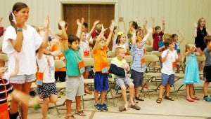 Messenger photo/Courtney Patterson Park Memorial United Methodist Church held its final night of Vacation Bible School Thursday night. Vacation Bible Schoolers raise their hands as they sing songs about God’s forgiveness during the opening ceremony. A kindergarten student places a painted fingerprint onto a cross while saying “I’m sorry, Jesus.” After making his print on the cross, he moved to the other side of the room to get on his knees and pray about things he had done wrong and ask forgiveness.