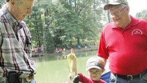 MESSENGER PHOTO/JAINE TREADWELL  Little Jack Redmon of Goshen was anxious to show off his stringer of catfish to John Dorrill, left, who along with his wife, Carol, hosted Pike County Kids Fishing Day at Clay Hill Farms Saturday. Mike Jones also stopped to admire the young fisherman’s catch of the day.