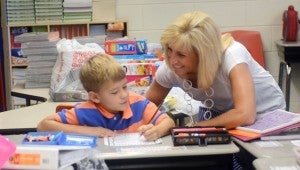 MESSENGER PHOTO/COURTNEY PATTERSON Laura Hixon, second grade teacher at Banks Primary School, assists her new student, Braxton Jordan, on the first day of school Monday.