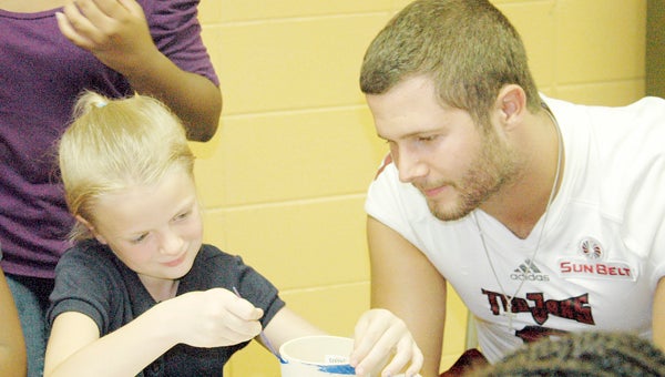 The Troy University football team visited the Boys and Girls Clubs of Pike and Surrounding Counties Monday afternoon. The players helped the kids with their homework, assisted them with a crafts project and challenged them to a game of kickball. Connor Bravard helps Izzy Taylor select the right color for her pottery piece.  MESSENGER PHOTO/JAINE TREADWELL