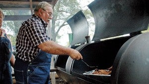 MESSENGER PHOTO/JAINE TREADWELL Brady Austin was one of the chief cooks at Tennille’s Saturday celebration. Austin is known for his grilled chicken and pork. He is also known for his cornbread but he has to have a skillet for that.
