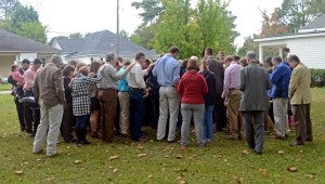 MESSENGER PHOTO/MIKE HENSLEY Church members and members of the community pray over the land that the next Habitat home will be built.