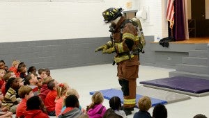 MESSENGER PHOTO/COURTNEY PATTERSON Chance shows the students what a fireman looks like in full gear, to show them they should not be afraid.
