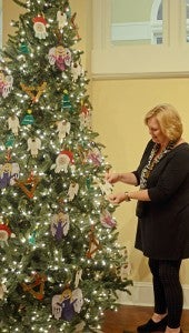 MESSENGER PHOTO/COURTNEY PATTERSON Vicki Pritchett, director of the Johnson Center for the Arts, admires ornaments on one of the many Christmas trees displayed in the main gallery of the Johnson Center. 
