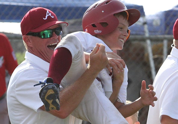 Photo/Dan Smith Troy assistant coach David Bradford celebrates with Slade Renfroe after Renfroe scores in the winning run in a 19-18 victory over South Carolina Saturday in the Machine Pitch World Series in Laurel, Ms.