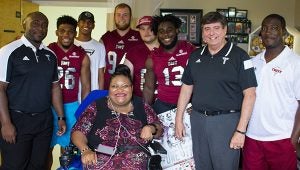 Lakesha Cannon and the Troy Trojans football team pose for a picture.