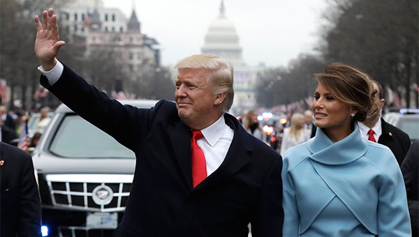 President Donald Trump waves as he walks with first lady Melania Trump during the inauguration parade on Pennsylvania Avenue in Washington, Friday, Jan. 20, 2016. (AP Photo/Evan Vucci, Pool)
