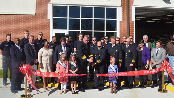Troy Fire Chief Michael Stephens cut the ribbon on Tuesday to officially open the third fire station for the City of Troy. Also pictured are firefighters from the Troy Fire Department. Current Troy City Council members, former coouncilmembers Johnny Witherington and Charlie “Sarge Dunn” and three local beauty pageant queens.